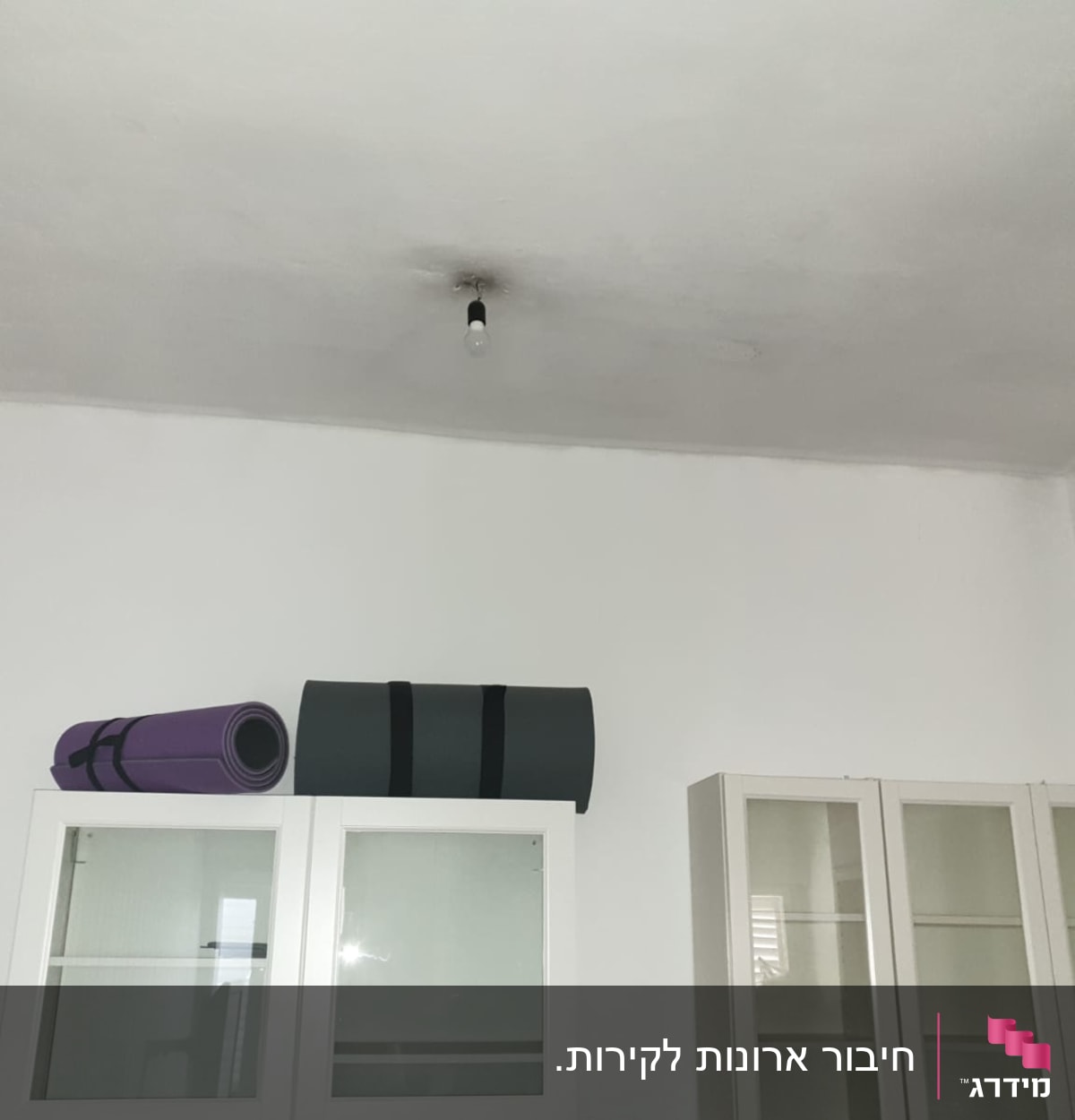 נורה חשופה בתקרה לבנה עם ארונות זכוכית